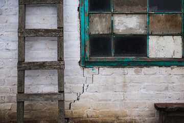 old cracked wall with shabby window and old wooden stepladder background