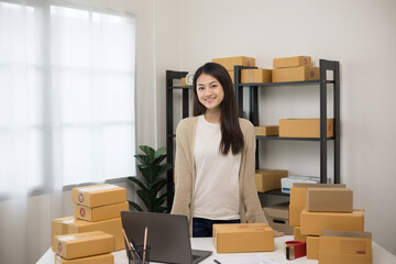Fototapeta na wymiar Beautiful young asian entrepreneur standing pose smiling to camera. Female small Business owner with box working at home. Startup freelance people with many parcel on background.