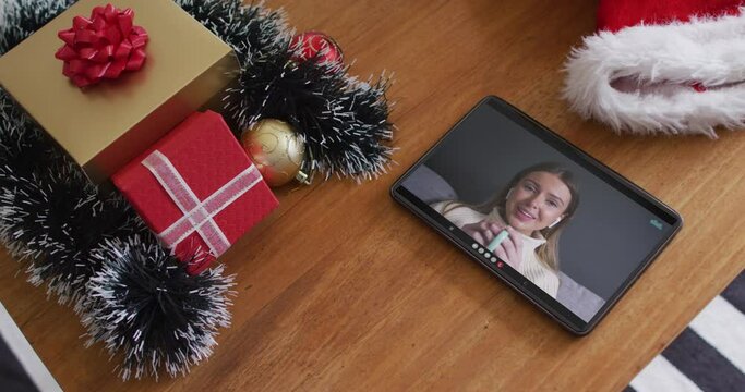 Smiling caucasian woman drinking coffee on christmas video call on tablet