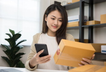 Fototapeta premium Startup Small business owner entrepreneur woman using smartphone scan qr code on product checking stock. Online business working at home. Contact customer on social network