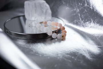 Beads from multi-colored natural stones lie on a snow-white stone, topaz and quartz, on a silver background