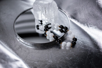 Beads from multi-colored natural stones lie on a snow-white stone, topaz and quartz, on a silver...
