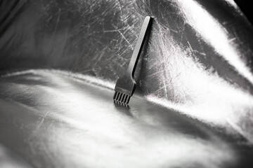 Metal iron tool, detail, lies on a silver background