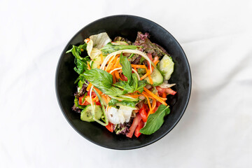 mixed salad in black bowl on white background