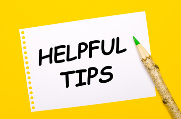 On a bright yellow background, a large wooden pencil and a white sheet of paper with the text HELPFUL TIPS