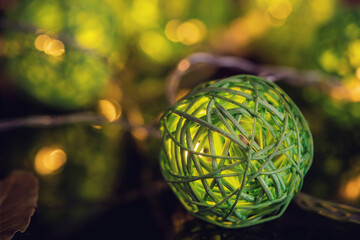 Green christmas ball in front of yellow christmas lights, close up, holiday concept, macro photography	