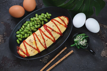 Omurice or japanese omelette stuffed with fried rice, view from above on a brown stone background,...