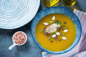 Pumpkin cream-soup served in a blue bowl with addition of cheese, high angle view, horizontal shot