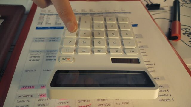 Person using a basic standard white calculator to create financial reports close up stock footage
