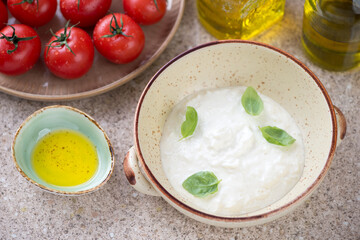 Bowl of stracciatella di bufala or italian cheese produced from buffalo milk, horizontal shot on a beige marble background