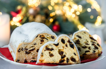 European pastry dessert with raisins, nuts, dried fruit and icing sugar. Christmas stollen pie and bokeh lights. Gluten off vegan dessert for winter holidays. Merry Christmas and Happy New Year.