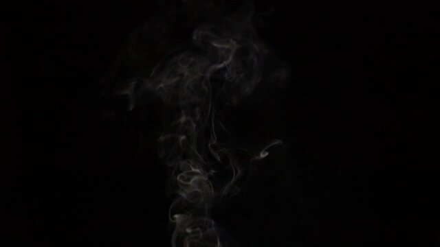Burning incense stick, scented smoke against black background, slow motion chillout footage