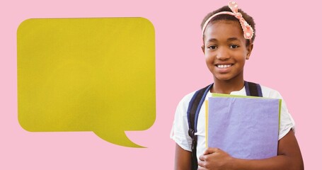 Digital composite of blank speech bubble with copy space by smiling schoolgirl holding books