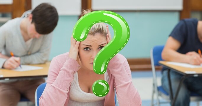 Digital composite of green question mark over tensed female student sitting in exam hall