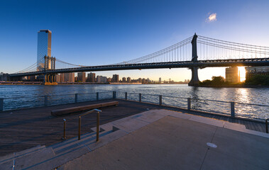 Travel to New York. The skyline of Manhattan photographed during a summer sunrise, view to Manhattan Bridge. Landmarks of United States of America. Skyscraper office buildings.
