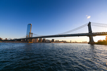 Obraz premium Travel to New York. The skyline of Manhattan photographed during a summer sunrise, view to Manhattan Bridge. Landmarks of United States of America. Skyscraper office buildings.