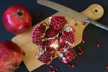 Ripe pomegranates on a dark background and pomegranate juice in a glass.