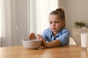 Cute little girl refusing to eat her breakfast at home