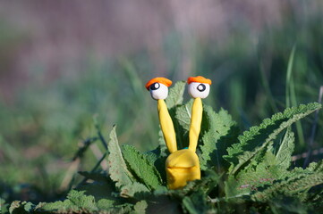 A snail made of plasticine in green grass.