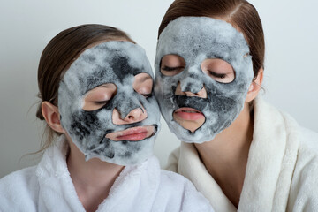 Two girls with a bubble mask on their faces. Little girl and young woman enjoy spa treatments. SPA...