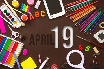 April 19th. Day 19 of month, Calendar date. School notebook and various stationery with calendar day. School and office supplies frame. Spring month, day of the year concept.