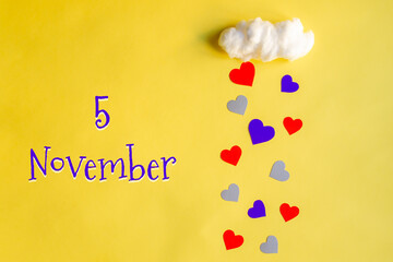 5 november day of month, colorful hearts rain from a white cotton cloud on a yellow background. Valentine's day, love and wedding concept