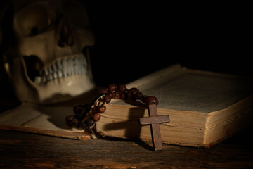 Conceptual image of rosary, ancient Bible and human skull as symbol of Christianity, religion,...