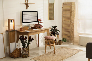 Comfortable workplace with modern computer and beautiful plants in room. Interior design