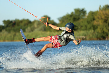 Teenage boy wakeboarding on river. Extreme water sport - obrazy, fototapety, plakaty
