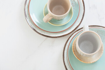 two ceramic cups and plates on white marble table