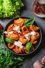 Italian pasta with mozzarella and fresh basil on rustic background