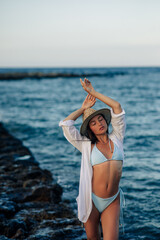 Young woman stands on rock near sea.