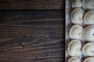 Meat or vegeterian dumplings, pelmeni on a wooden board. Russian national food. Close up top view with copy space.