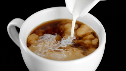 Coffee creamer. Pour cream in black coffee close up