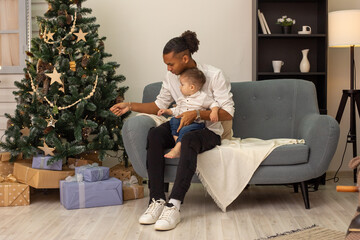 Young father and little son are sitting in the living room decorated for Christmas