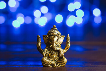 Fototapeta premium Golden lord ganesha sclupture over blue illuminated background. Celebrate lord ganesha festival