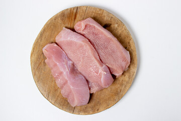 Raw turkey steaks on a white plate. Turkey breast fillet on a wooden board. Diet meat