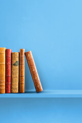 Row of old books on blue shelf. Vertical background