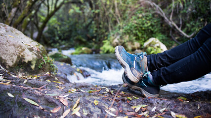Detail of the boots of a woman hiking along the bank of a river