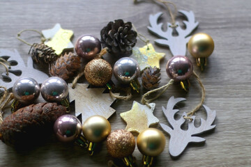 Various wooden Christmas ornaments, golden baubles and pine cones on wooden background. Selective focus.