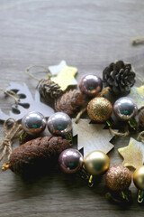 Various wooden Christmas ornaments, golden baubles and pine cones on wooden background. Selective focus.