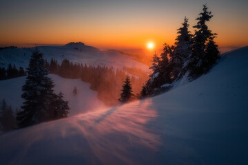 Amazing beautiful sunrise during a blizzard in the mountains with a warm golden orange light
