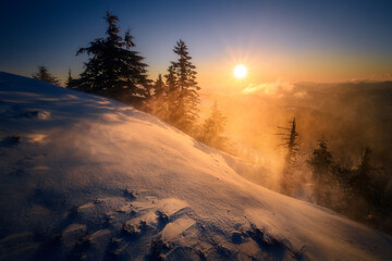 Beautiful sunrise landscape scene on a winter morning with high winds blowing the snow