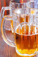 Two large glasses of beer on a wooden table