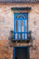 Fototapeta na wymiar Detail of a balcony with a charming, decorative fence, doors and a planter in Old Havana.