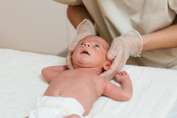 Physiotherapist doing a positional plagiocephaly correction on a newborn baby in a therapy center.