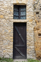 The old door with window in the stone facade of a historic building.