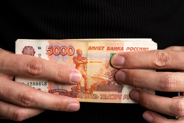 Close-up men's hands hold a wad of Russian money five thousand bills.