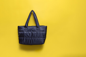 The bag is black textile on a yellow background with a shadow.
