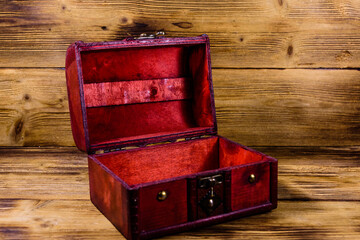 Opened vintage chest from red wood on wooden background